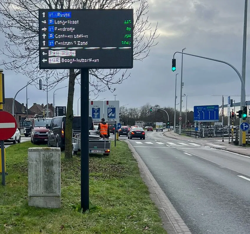 Techniciens utilisant une nacelle pour installer un panneau directionnel sur un poteau en bord de route
